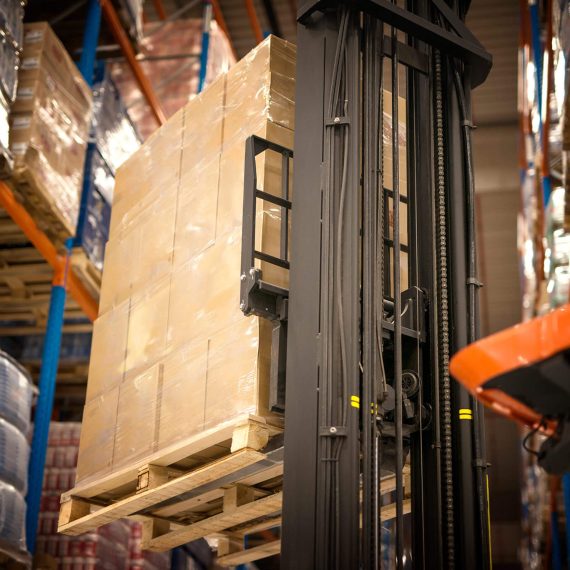 industrial-forklift-machine-lifting-palette-full-cardboard-boxes-placing-them-shelves-distribution-warehouse-facility